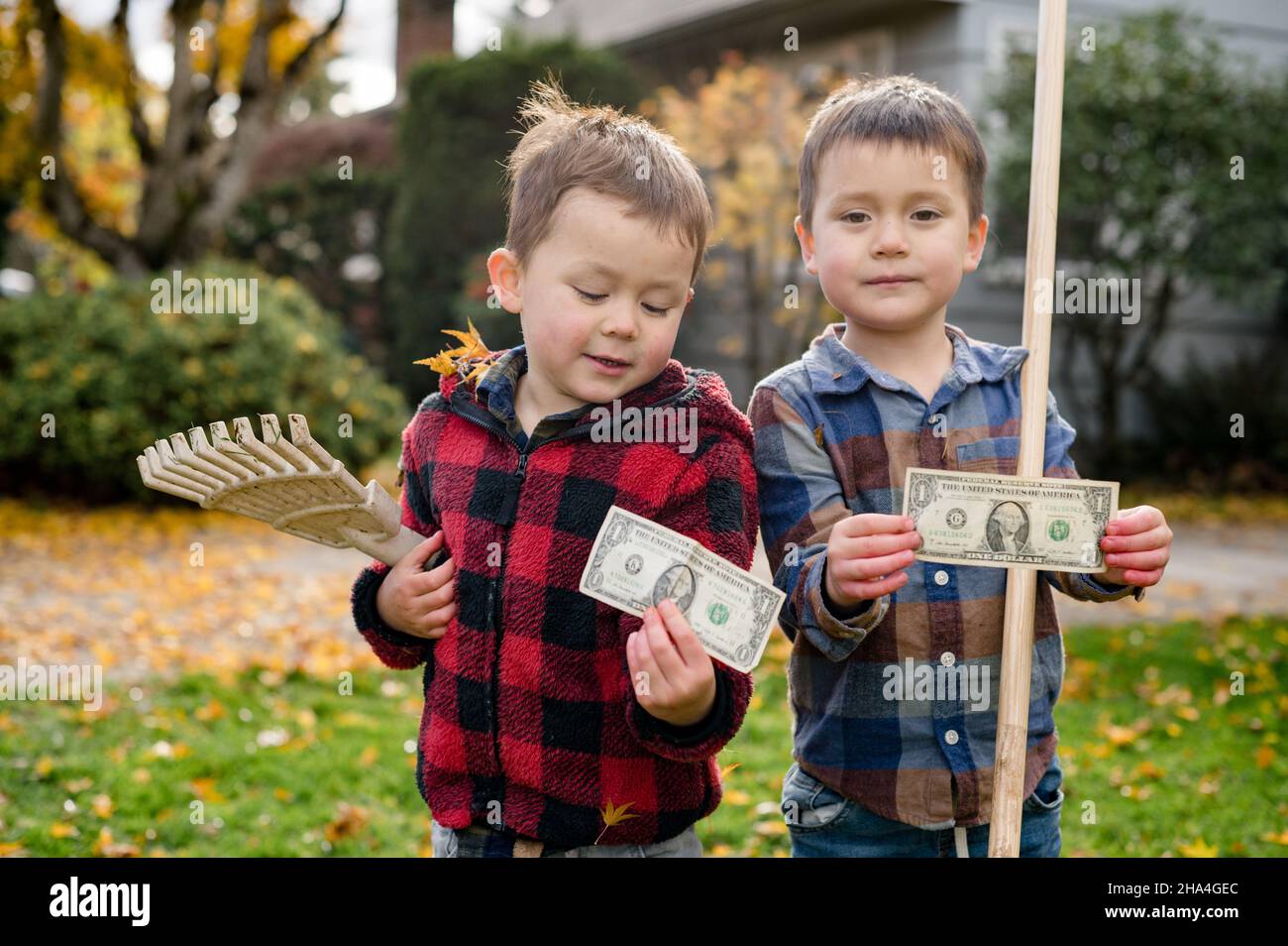 Ritratto di due fratelli che tengono conto delle foglie di rastrellatura Foto Stock