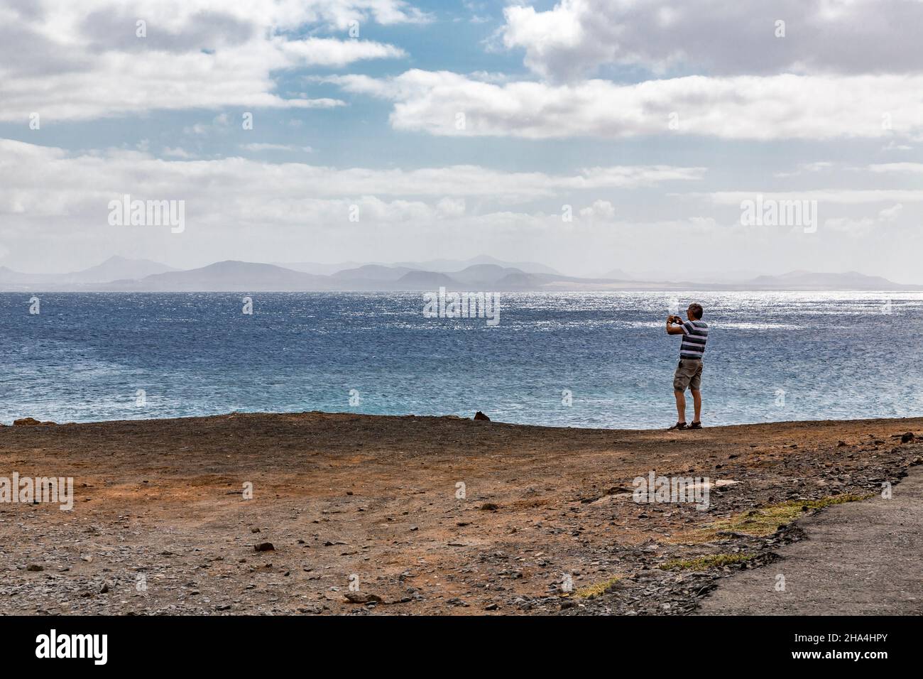 l'uomo anziano fotografa l'isola di fuerteventura con uno smartphone,punta pechiguera,playa blanca,lanzarote,canari,isole canarie,spagna,europa Foto Stock