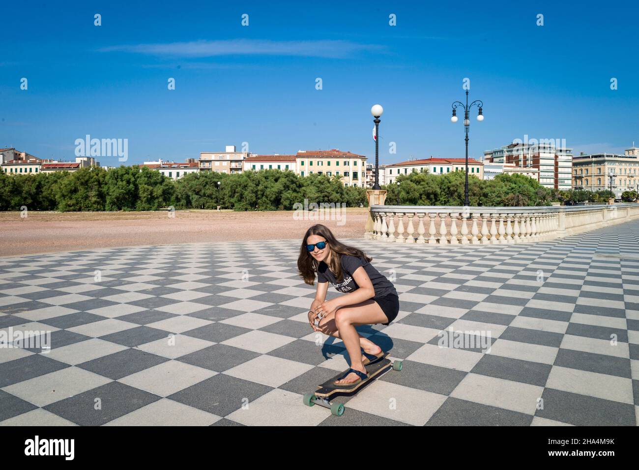 skater ragazza pattinare e saltare sulla terrazza mascagni a livorno, italia. il suo ampio belvedere sinuoso verso il mare con una superficie di pavimentazione di 8700 mq come una scacchiera e 4,100 balaustre Foto Stock