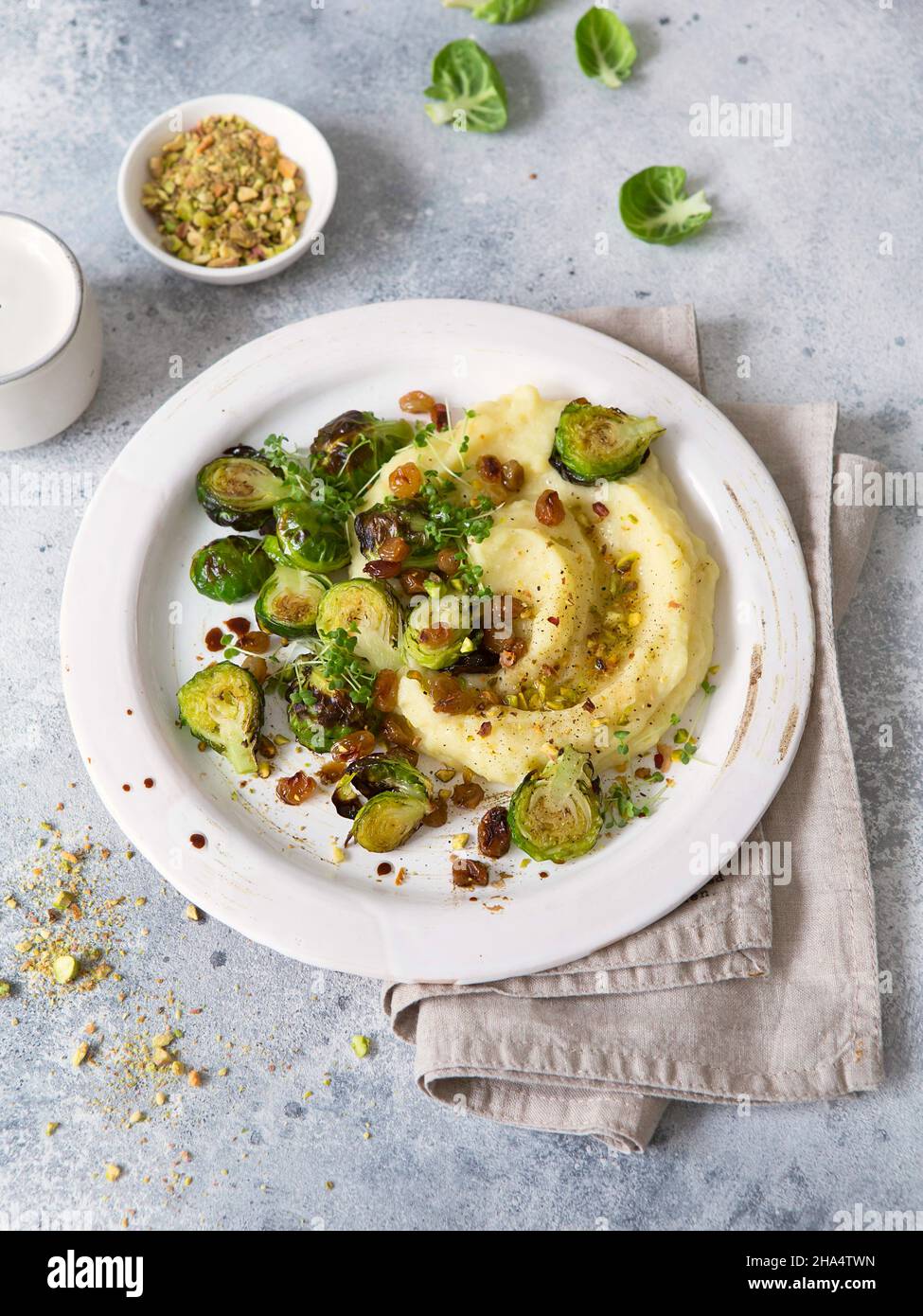 Bruxelles germogli con pistacchi, uvetta e Skordalia (purè di patate). Preparazione sana del pasto. Piatti a base di piante. Vita verde. Ricetta vegana. F Foto Stock