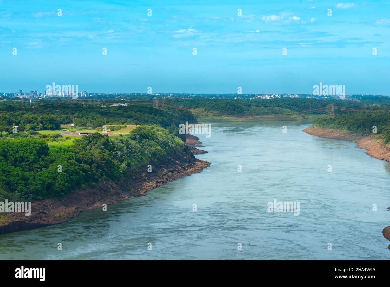 Fiume Parana al confine tra Brasile e Paraguay con una vista dello skyline distante Paraguayan città di Ciudad del Este. Foto Stock