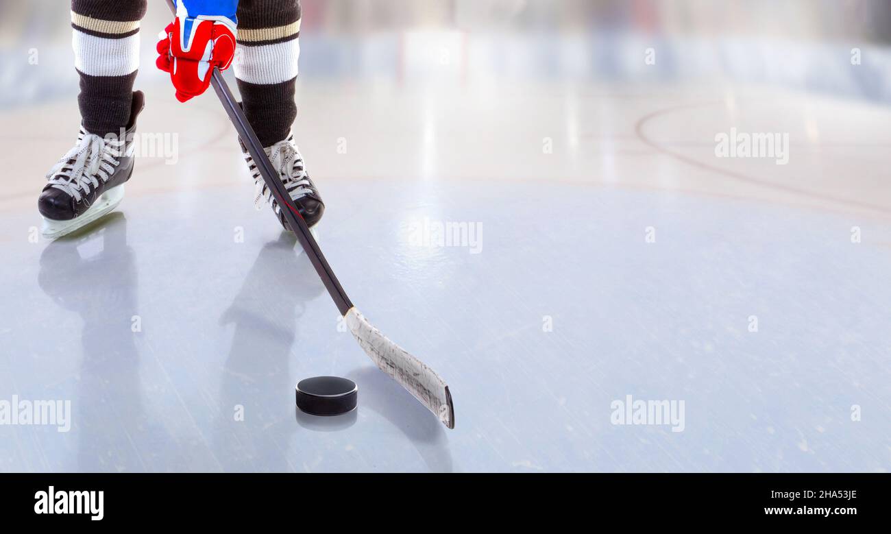 Vista ad angolo basso del giocatore di hockey su ghiaccio con bastone sulla pista di ghiaccio che controlla il puck e lo spazio di copia. Foto Stock