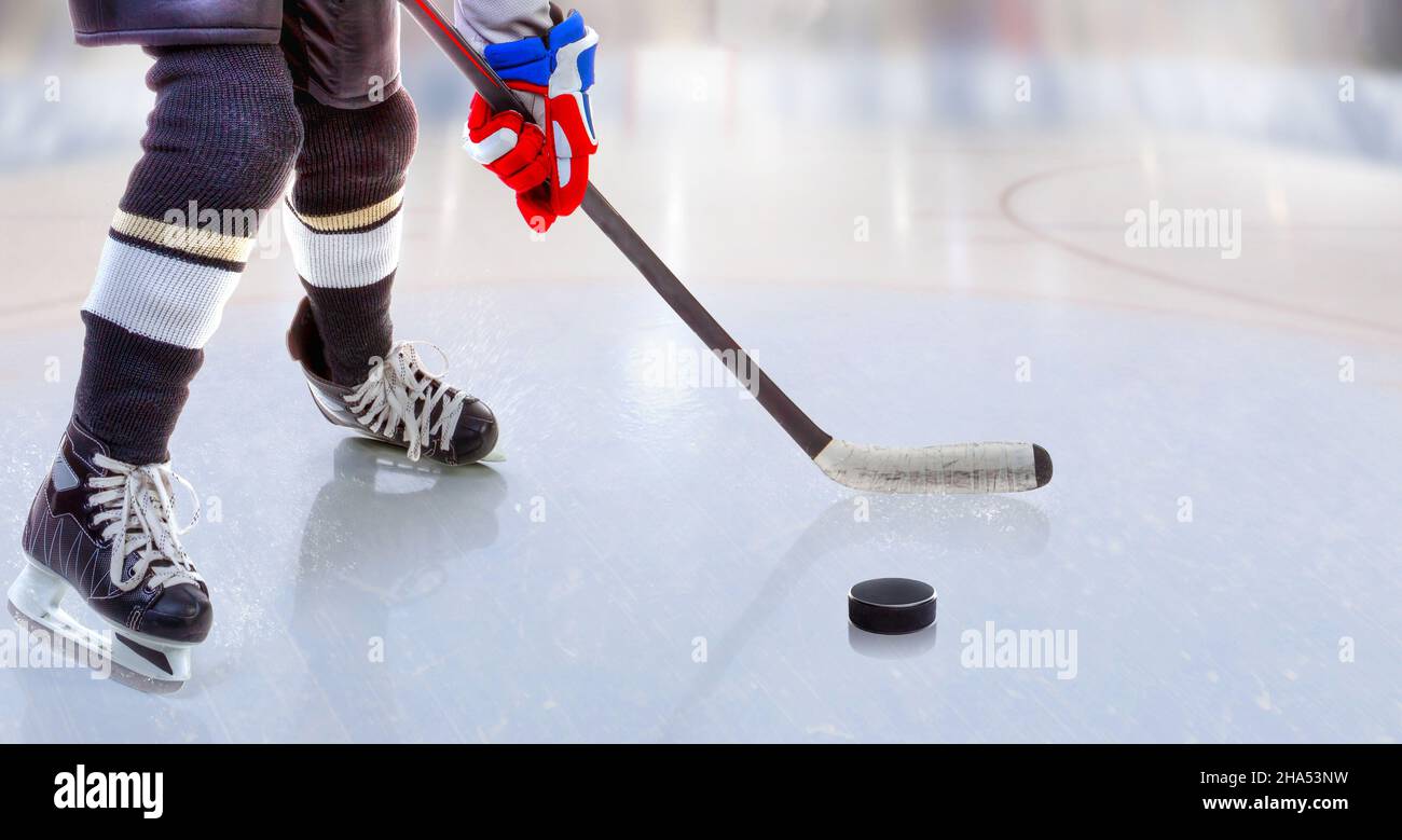 Vista ad angolo basso del giocatore di hockey su ghiaccio con bastone sulla pista di ghiaccio che controlla il puck e lo spazio di copia. Foto Stock
