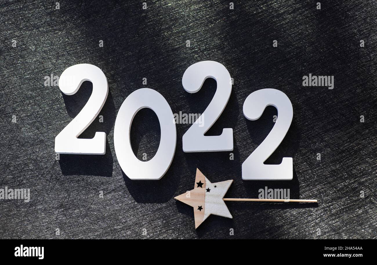 Cartello di Capodanno 2022 in legno su sfondo festivo con spazio copia. Legno dipinto di bianco ha creato l'iscrizione numero 2022 su sfondo nero. Foto Stock