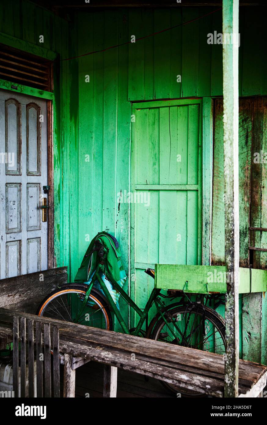 Una bicicletta verde si appoggia contro una casa dipinta di verde a Palangkaraya, Kalimantan centrale, Borneo Indonesia. Foto Stock