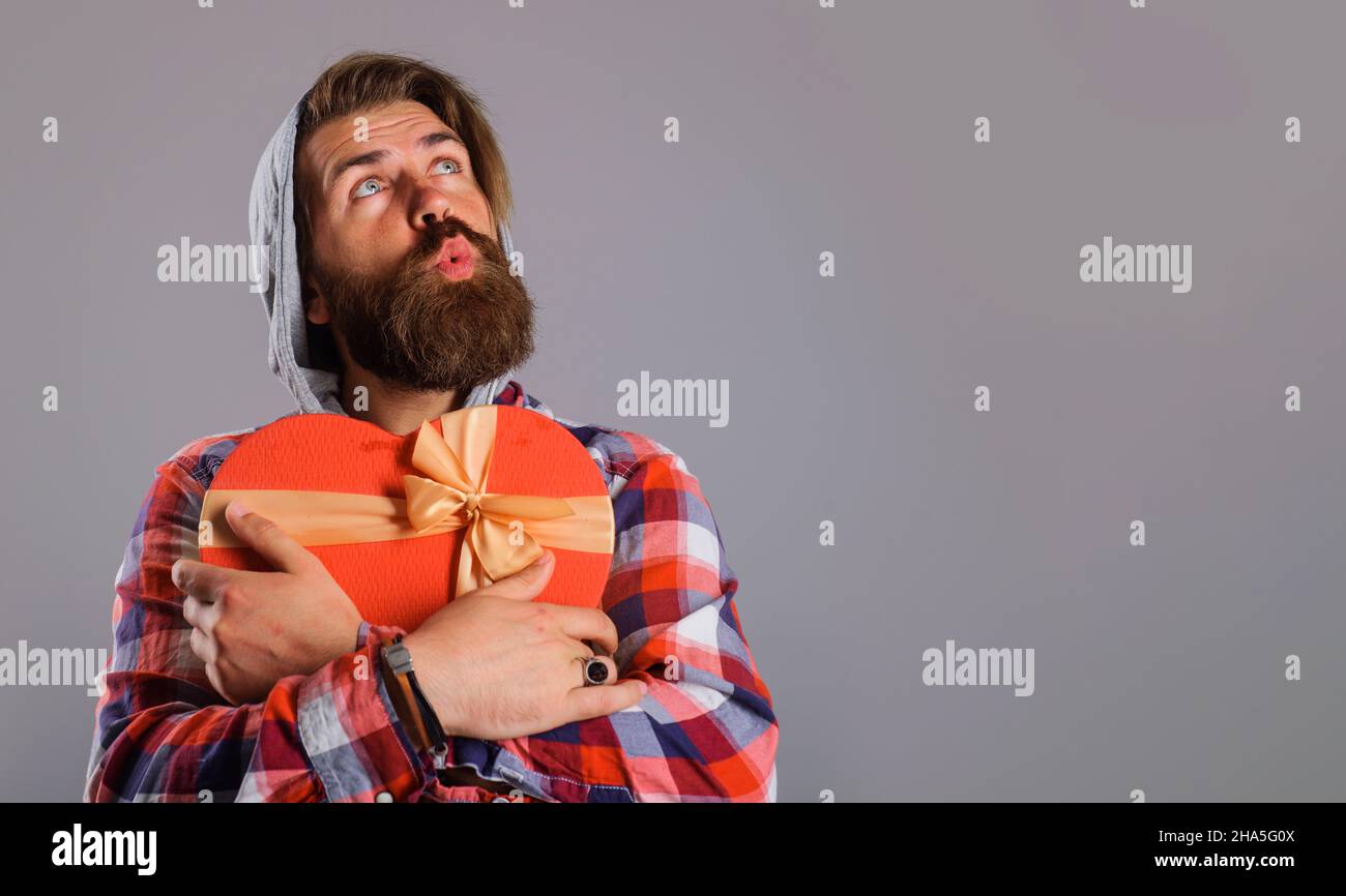 Uomo bearded con scatola del regalo a forma di cuore. Presenti con amore. È il momento di presentare. San Valentino. Spazio di copia Foto Stock