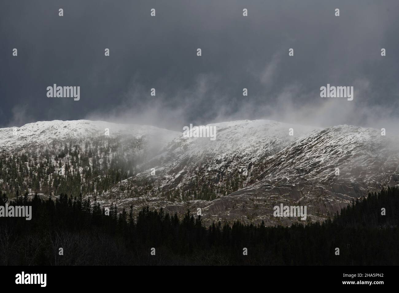 nuvole scure su una cima di montagna con neve, kongsmoen, nordland, norvegia Foto Stock