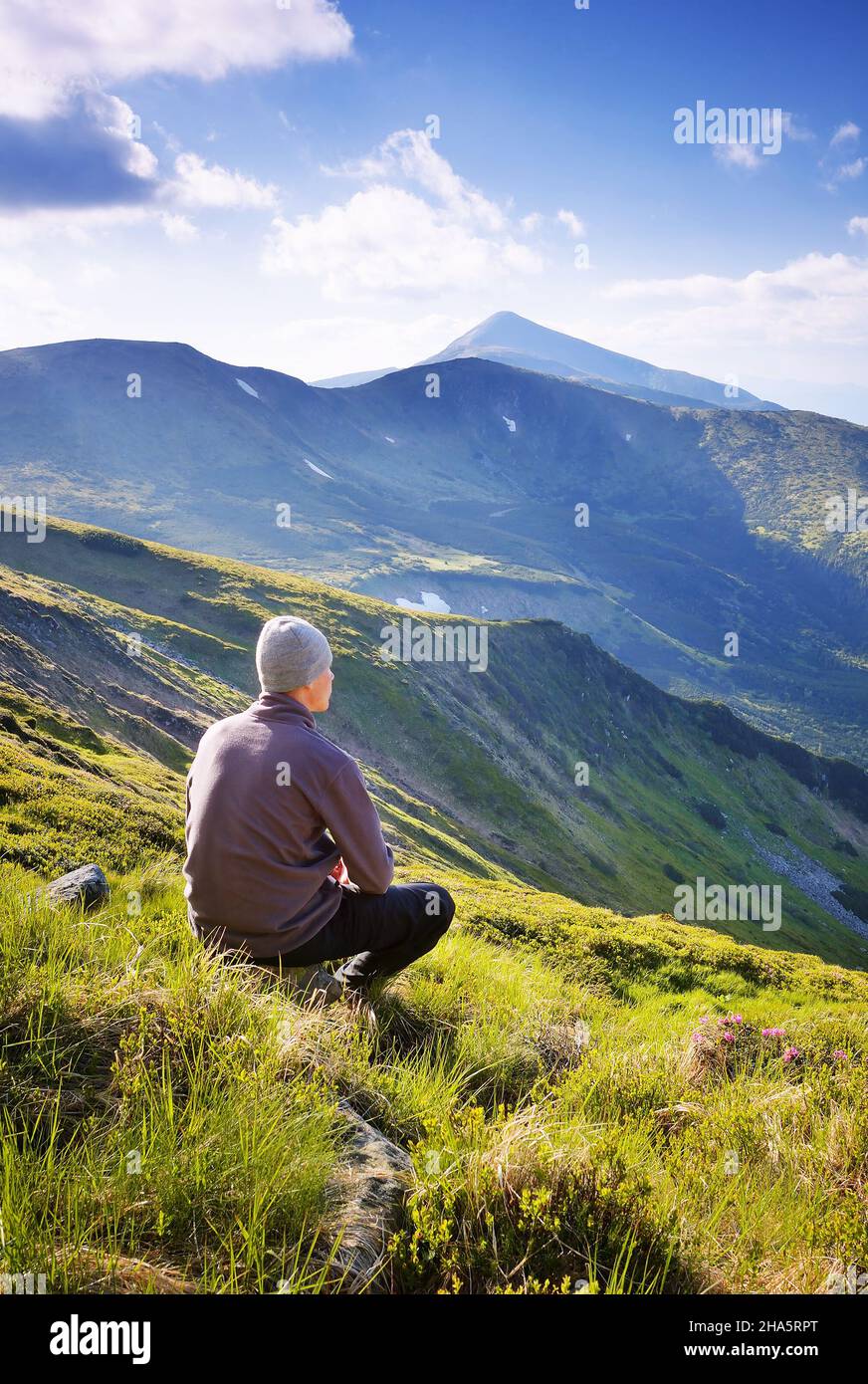 Uomo turistico che guarda le montagne. Paesaggio estivo in una giornata di sole Foto Stock