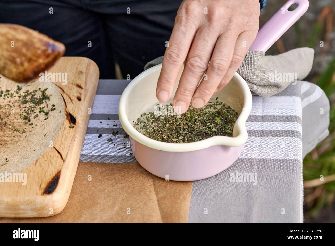 fasi nella produzione di caramelle di timo,foglie di timo schiacciate vengono cosparse in una pentola di zucchero di betulla fuso Foto Stock