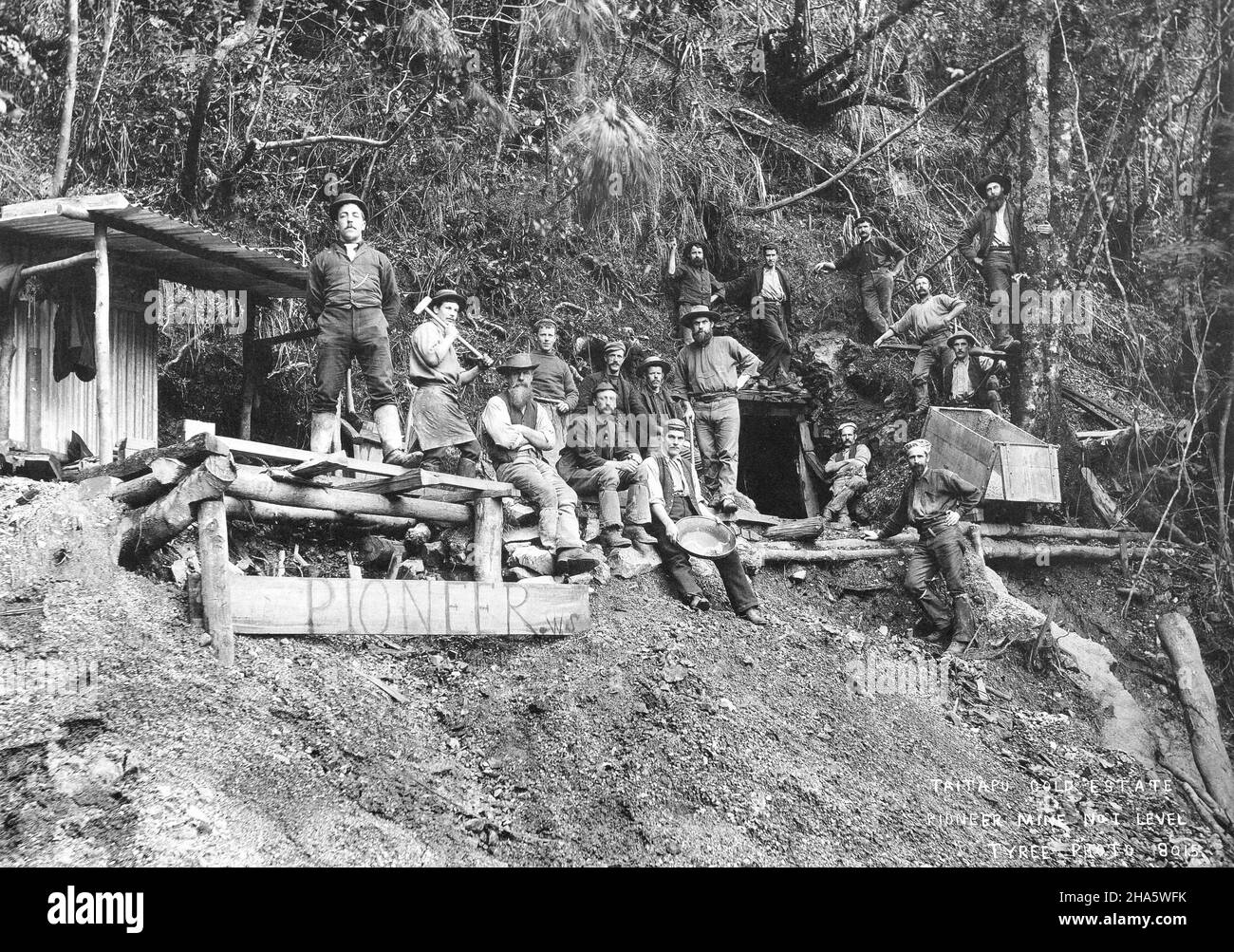 Un gruppo di 17 minatori presso la miniera d'oro Pioneer presso la tenuta d'oro Tai Tapu vicino a Golden Bay, nuova Zelanda, intorno al 1895. Un riparo in ferro ondulato è sulla sinistra. Foto Stock