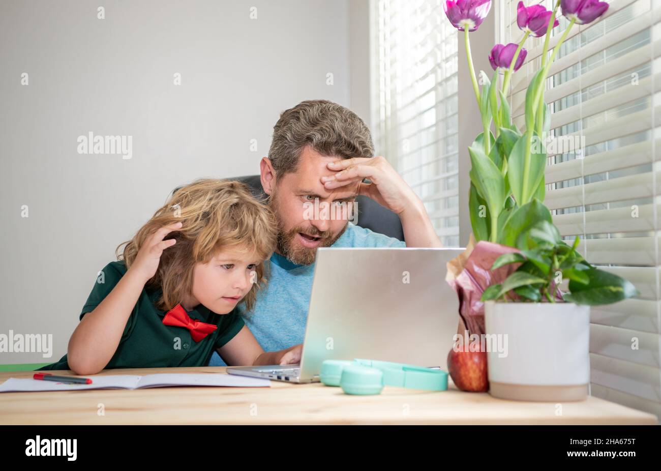 insegnante o papà uomo maturo che aiuta il figlio del bambino con i compiti a scuola sul computer, videoconferenza Foto Stock
