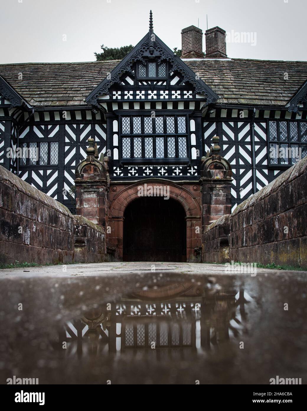 Il riflesso di una pozza che cattura la facciata tudor. Speke Hall è una casa padronale Tudor con pareti in legno a Speke, Liverpool, Inghilterra. Foto Stock
