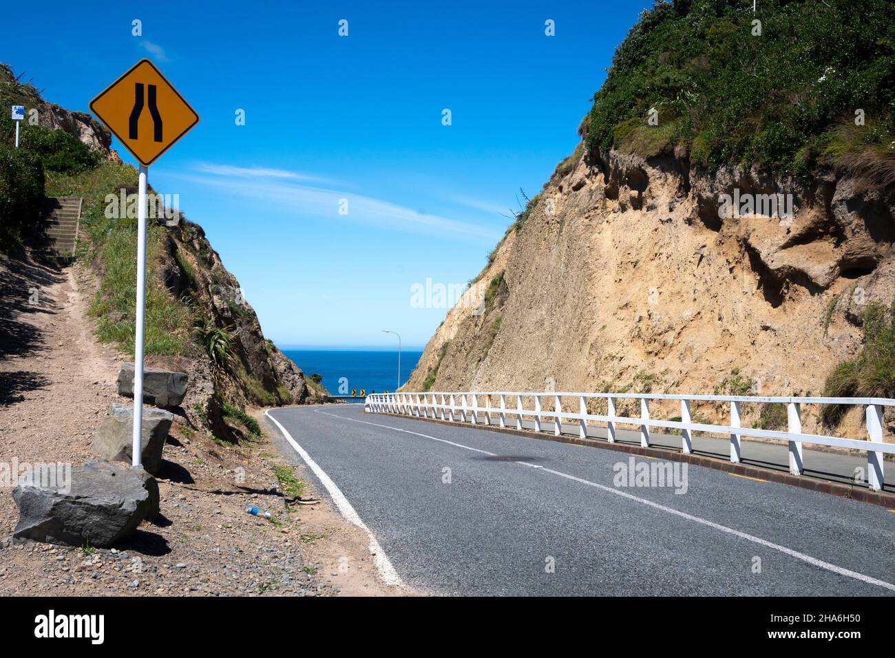 Strada stretta attraverso il taglio al mare, Passo di Branda, Seatoun, Wellington, Isola del Nord, Nuova Zelanda Foto Stock