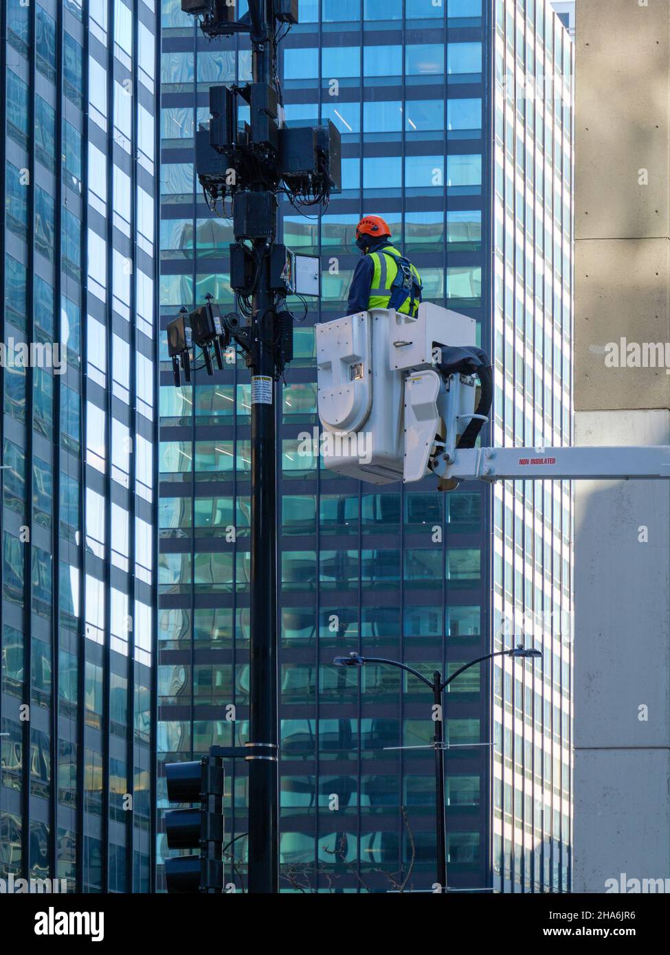 Tecnico che esegue la manutenzione delle antenne cellulari sul polo luminoso. Chicago, Illinois. Foto Stock