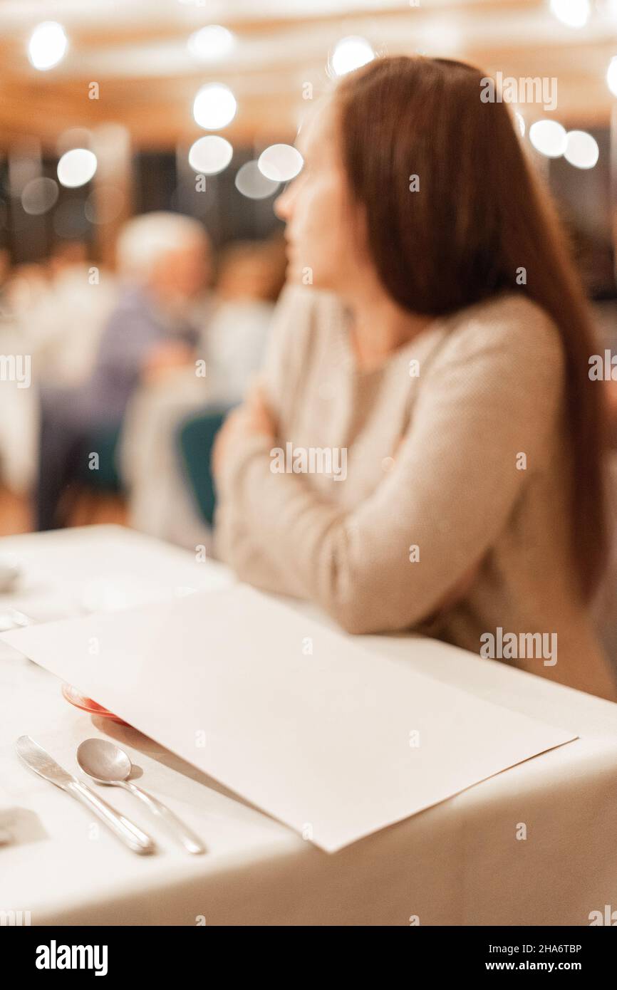 Menu della sala da pranzo dell'hotel mentre una donna aspetta la colazione. Foto Stock