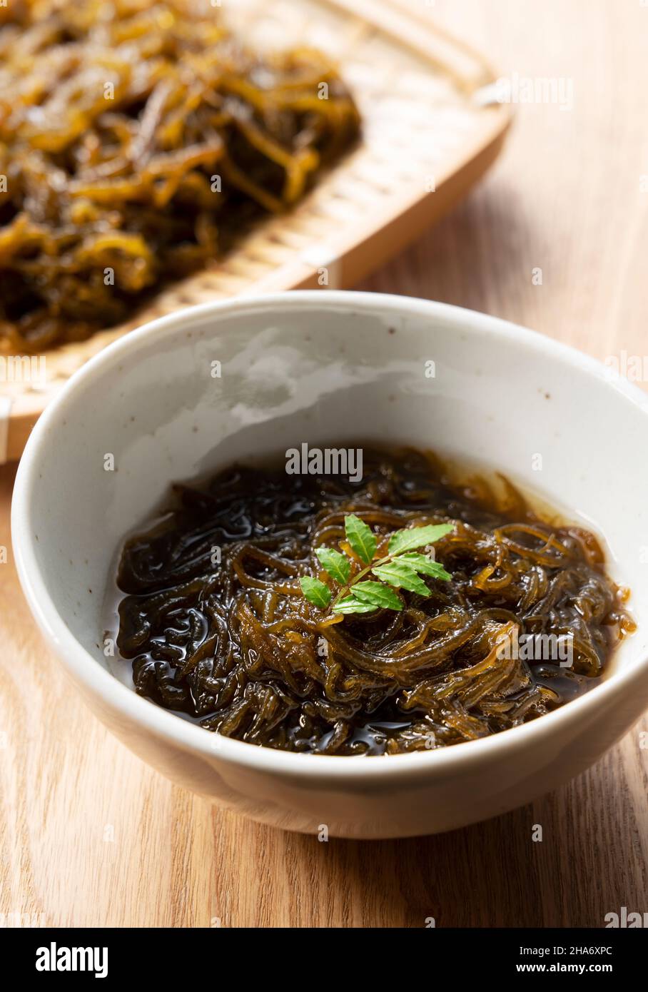 Mozuku su un tavolo di legno. Mozuku è una prelibatezza Okinawan. Si tratta di un tipo di alga scura, filata condita con aceto Foto Stock