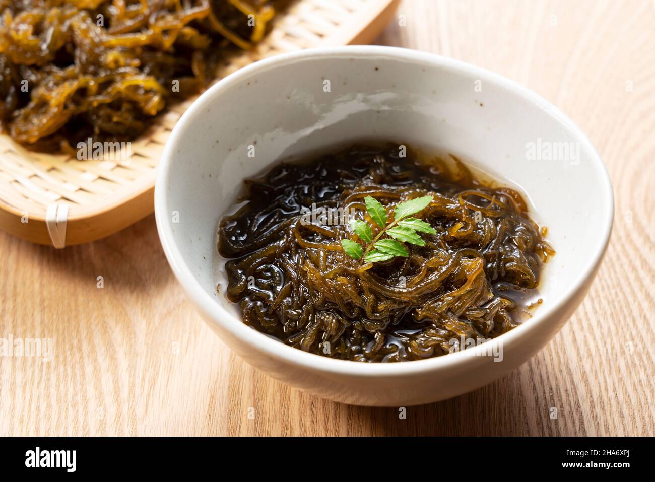 Mozuku su un tavolo di legno. Mozuku è una prelibatezza Okinawan. Si tratta di un tipo di alga scura, filata condita con aceto Foto Stock