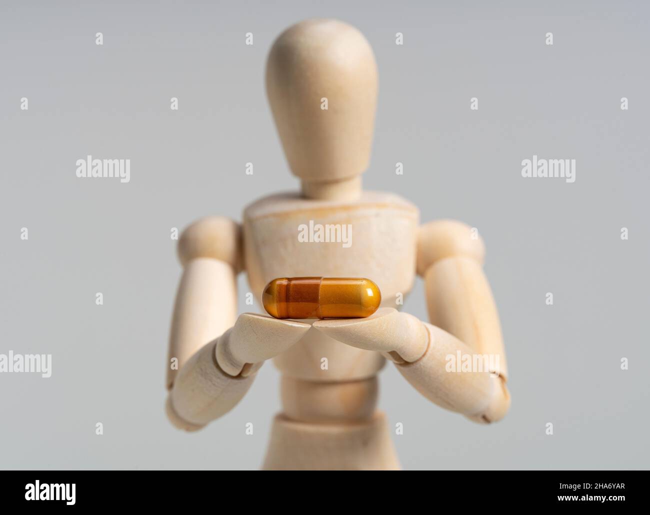 Manichino in legno con pillole su sfondo bianco. Concetto di prodotti farmaceutici e integratori. Foto Stock