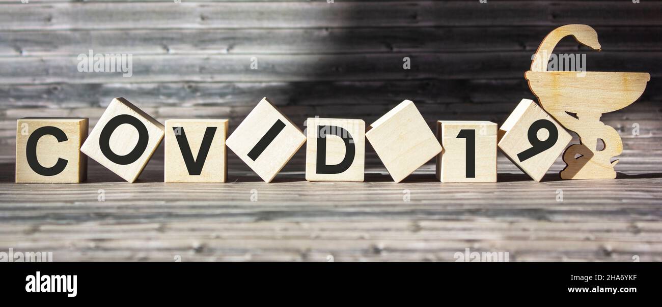 Virus della pandemia mondiale COVID 19 parole su blocchi di legno con sfondo marrone Foto Stock