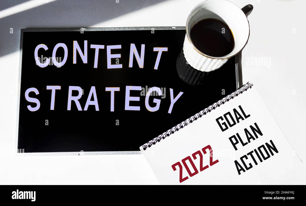 2022, obiettivo, piano, testo di azione su blocco note con una tazza di caffè, su uno sfondo bianco e nero.motivazione di affari. Strategia dei contenuti per il nuovo anno 2022. Foto Stock