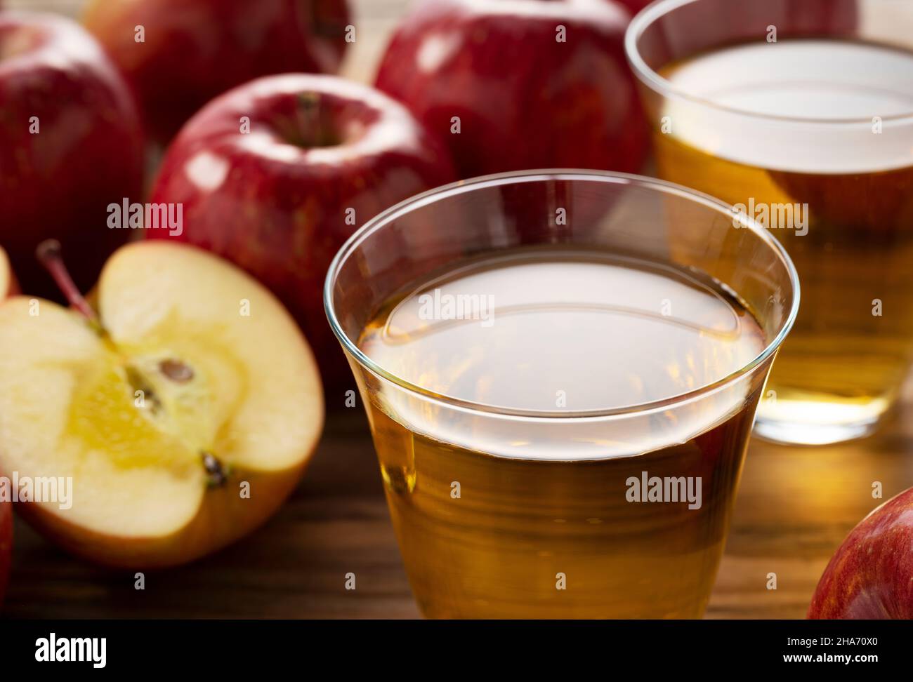 Succo di mela in una tazza di vetro con un albero sullo sfondo e un sacco di mele intorno. Foto Stock