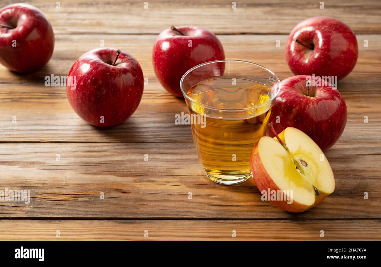 Succo di mela in una tazza di vetro con un albero sullo sfondo e un sacco di mele intorno. Foto Stock