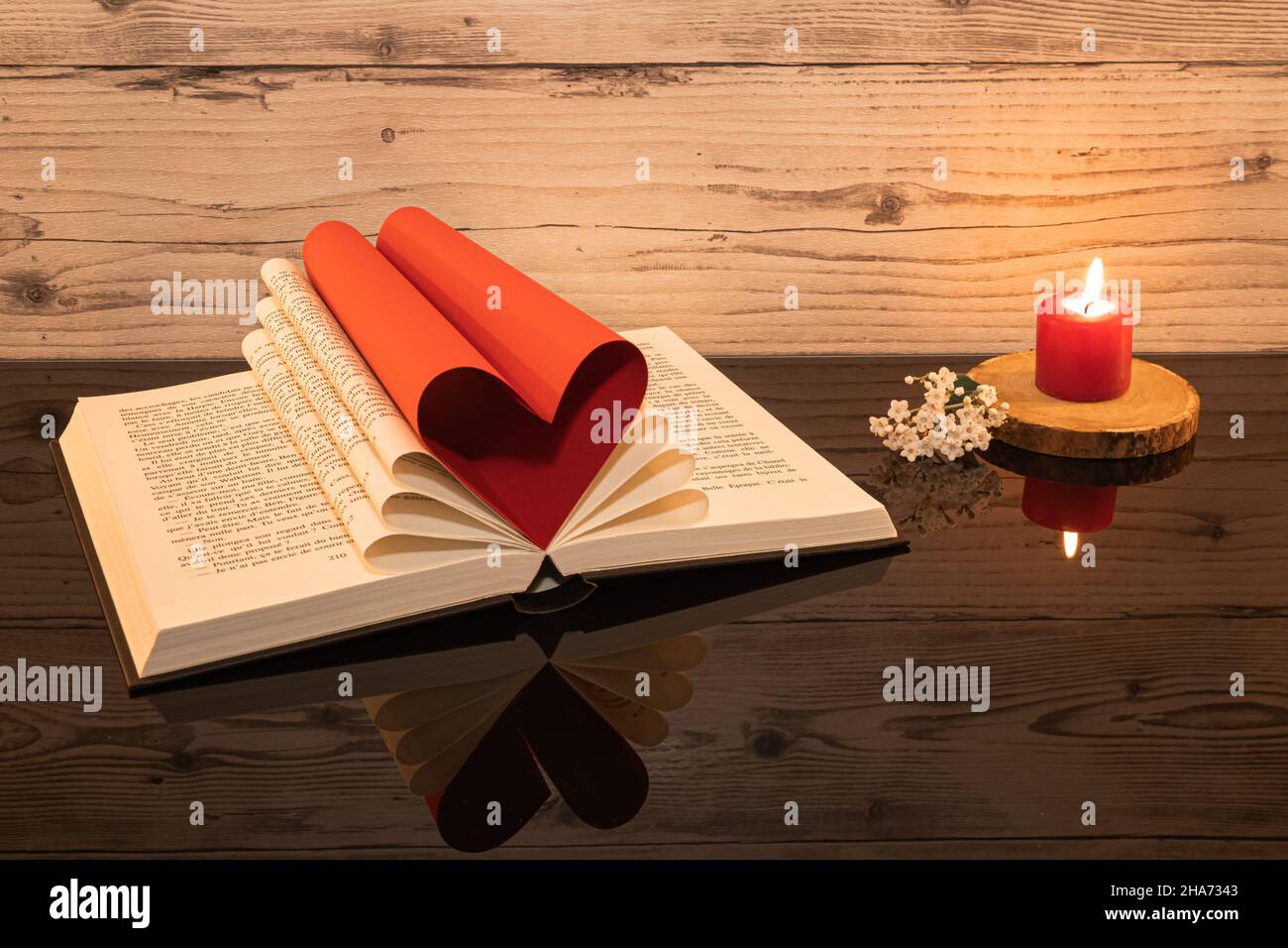 Libro piegato a forma di cuore su sfondo di legno. Foto Stock