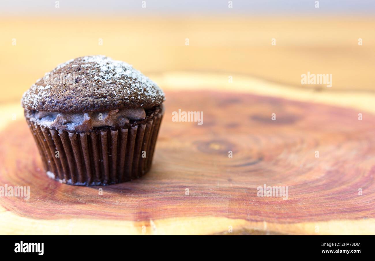 Torta al cioccolato Victoria Sponge Mini Cup riempita con crema di cacao e spolverata con zucchero su tavola di legno di ciliegio con spazio per il testo Foto Stock