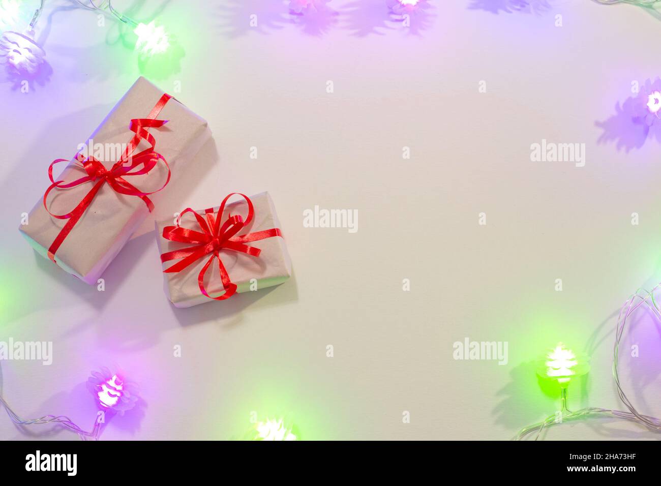 Sfondo con le ghirlande festive di Capodanno, luce viola brillante, piccole confezioni regalo, con posto per il testo. Foto Stock