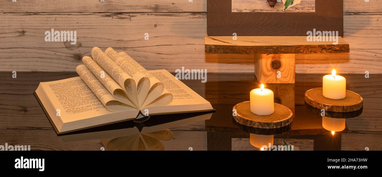 Libro piegato a forma di cuore su sfondo di legno. Foto Stock