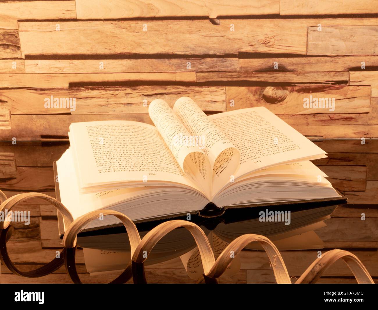 Libro piegato a forma di cuore su sfondo di legno. Foto Stock