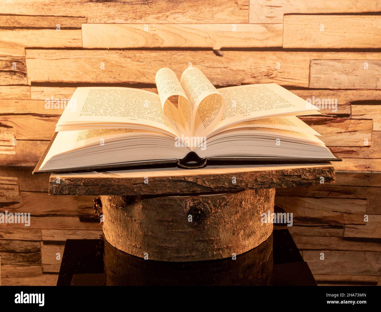 Libro piegato a forma di cuore su sfondo di legno. Foto Stock
