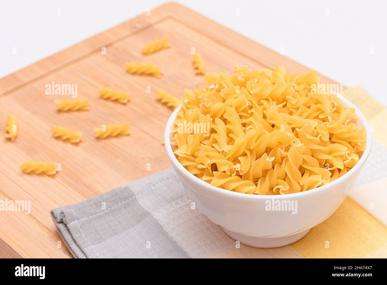 Pasta di Fusilli non cotta in ciotola bianca su tavola di legno. Macaroni crudi e secchi. Cibo malsano e grasso. Cultura Italiana Foto Stock
