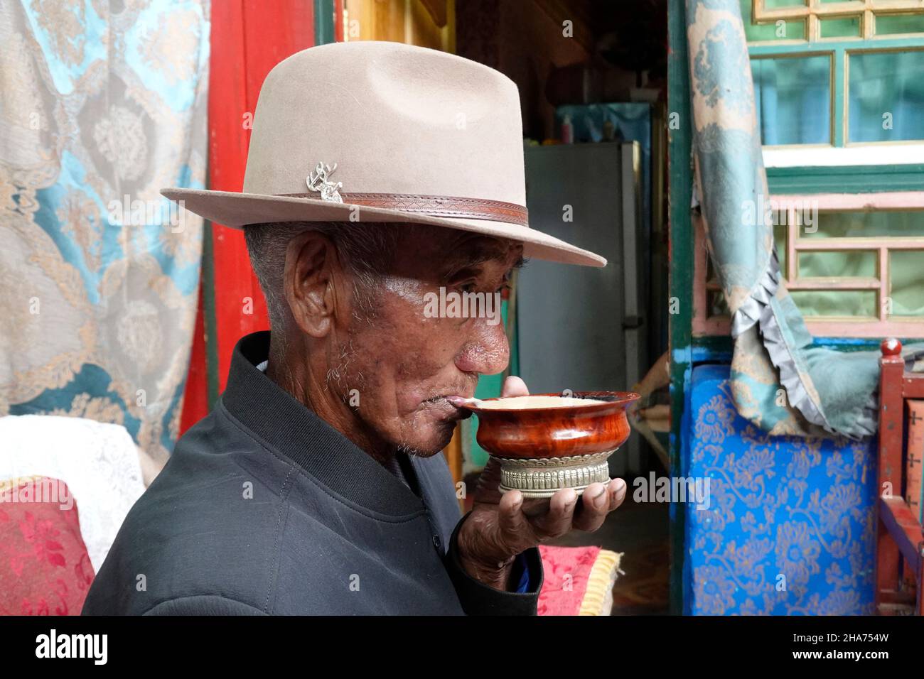 (211211) -- LHASA, 11 dicembre 2021 (Xinhua) -- Shodolek beve tè al burro a casa sua nel villaggio di Gaiba, distretto di Nedong di Shannan, regione autonoma del Tibet della Cina sud-occidentale, 23 giugno 2021. Nato nel 1946, Shodolek e tutta la sua famiglia erano un tempo servi che dovevano fare lavori pesanti senza fine prima della riforma democratica in Tibet nel 1959. "Il proprietario del serpente ci ha dato, una famiglia di cinque, solo un po 'di tsamba scaduto per i pasti di tutti i giorni", ha ricordato Shodolek. A quel tempo, i serpenti erano sempre stati picchiati dai proprietari di serpenti oltre a soffrire la fame e il freddo. All'età di soli 40 anni, madre di Shodolek passò via a causa di Foto Stock