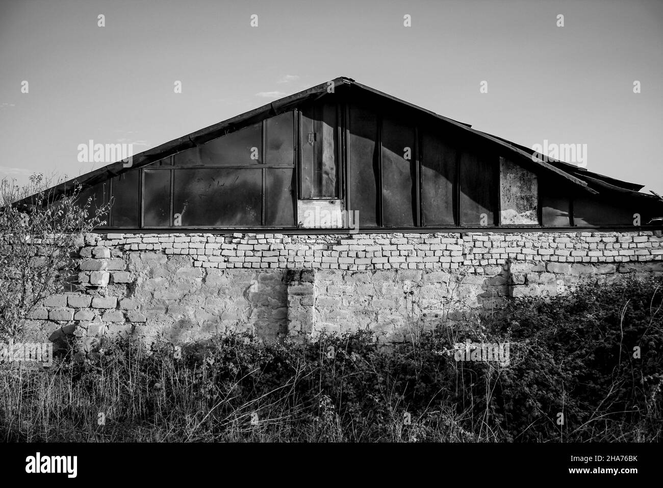 Vecchio edificio brutto con un tetto arrugginito in bianco e nero. Foto Stock