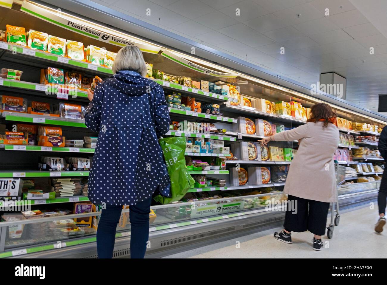 Vista posteriore dei clienti donne che guardano a prodotti alimentari vegani a base di piante e cibi confezionati vegetariani sugli scaffali del supermercato Waitrose UK KATHY DEWITT Foto Stock