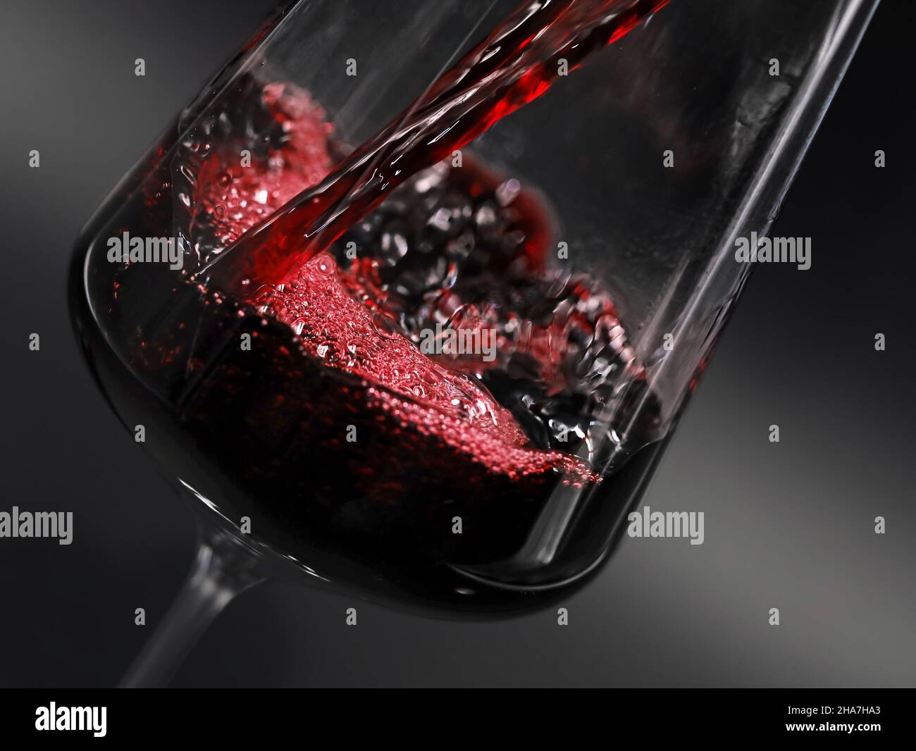 primo piano del vino rosso che si versa in un bicchiere isolato su sfondo nero Foto Stock