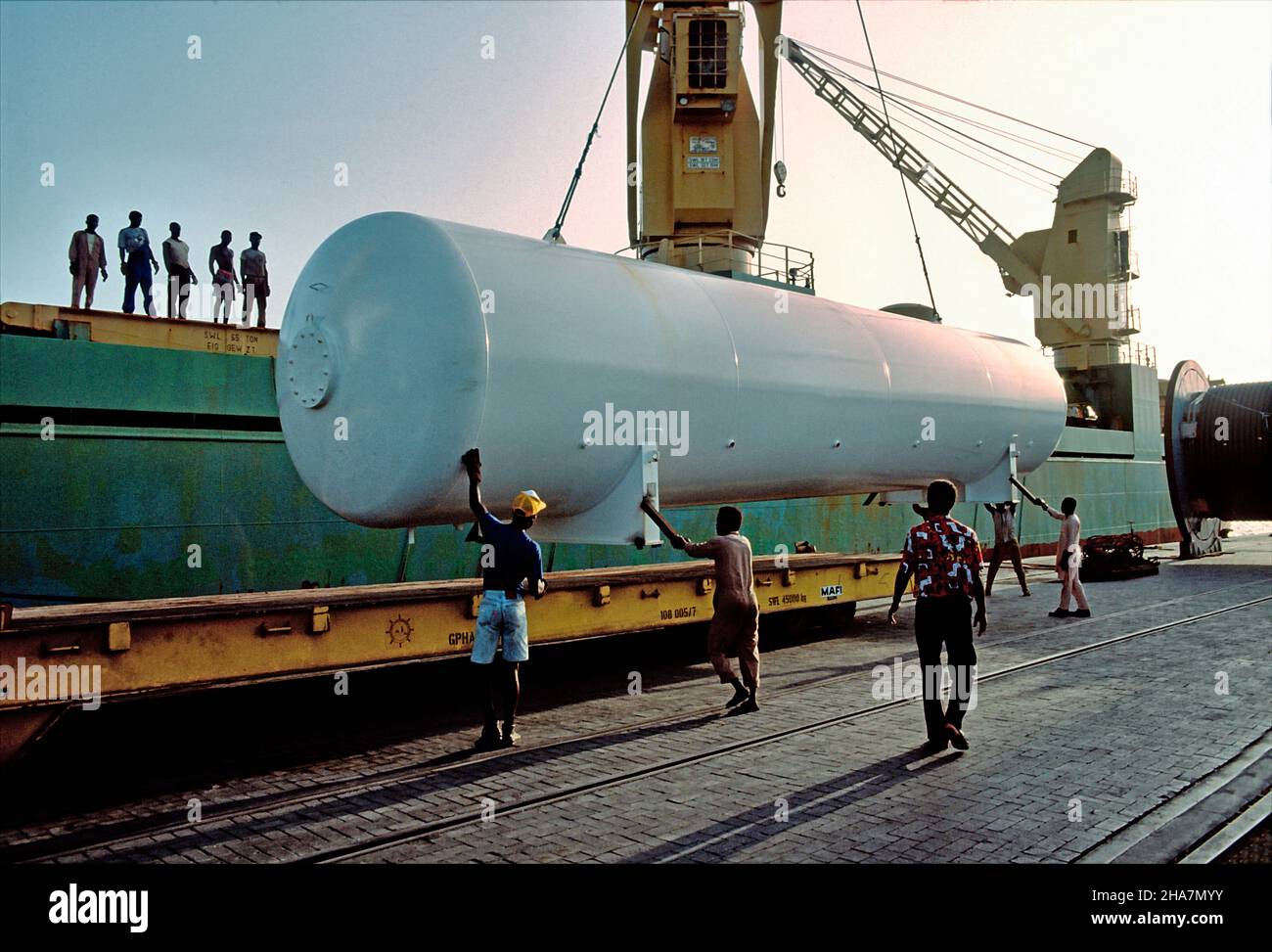 Il carico pesante, un'attrezzatura di perforazione, viene trasbordato su un rimorchio mafi nel porto di Tima, Ghana. Foto Stock