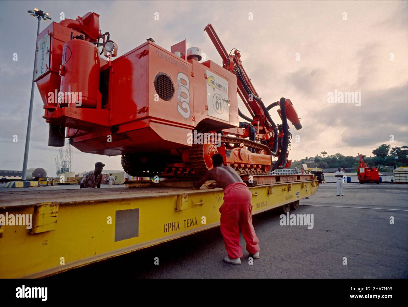 Il carico pesante, un'attrezzatura di perforazione, viene trasbordato su un rimorchio mafi nel porto di Tima, Ghana. Foto Stock