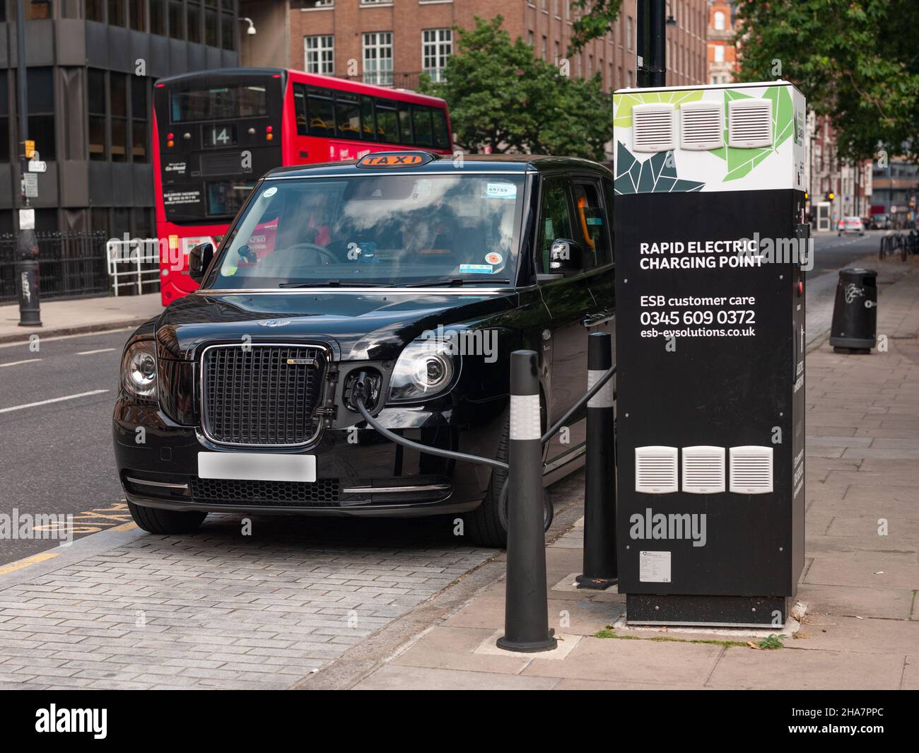 London Taxi presso il punto di ricarica elettrica Foto Stock