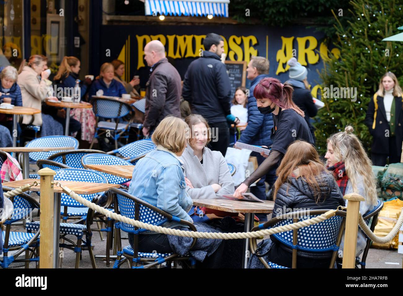 Clifton, Bristol, Regno Unito. 11th Dic 2021. Le persone fanno i loro acquisti pre-Natale in up-market Clifton per le preoccupazioni sulla variante Omicron Covid-19 aumento. Alcune persone indossano maschere all'esterno e altre no. È sempre il momento di fermarsi al Primrose Cafe. Credit: JMF News/Alamy Live News Foto Stock