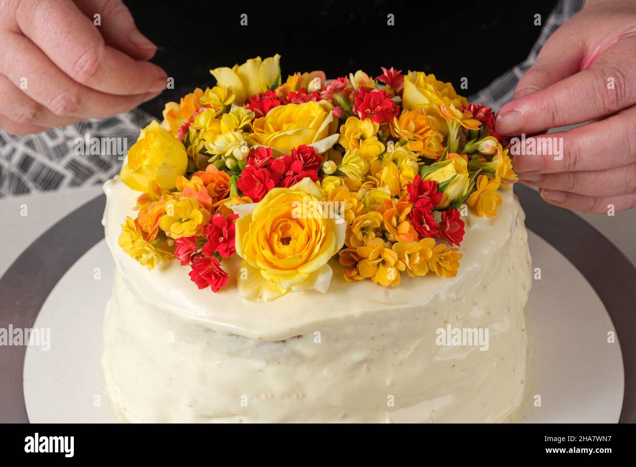 Primo piano di fiori gialli che decorano una torta alla vaniglia con ganache di cioccolato bianco. Foto Stock