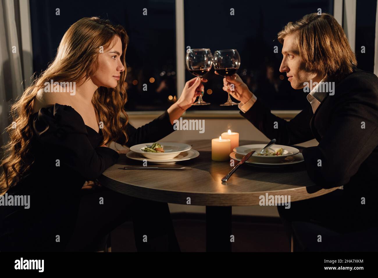 Coppia in amore tenere bicchieri di vino a un tavolo in un ristorante, primo piano, data di San Valentino, cena romantica, toast Foto Stock