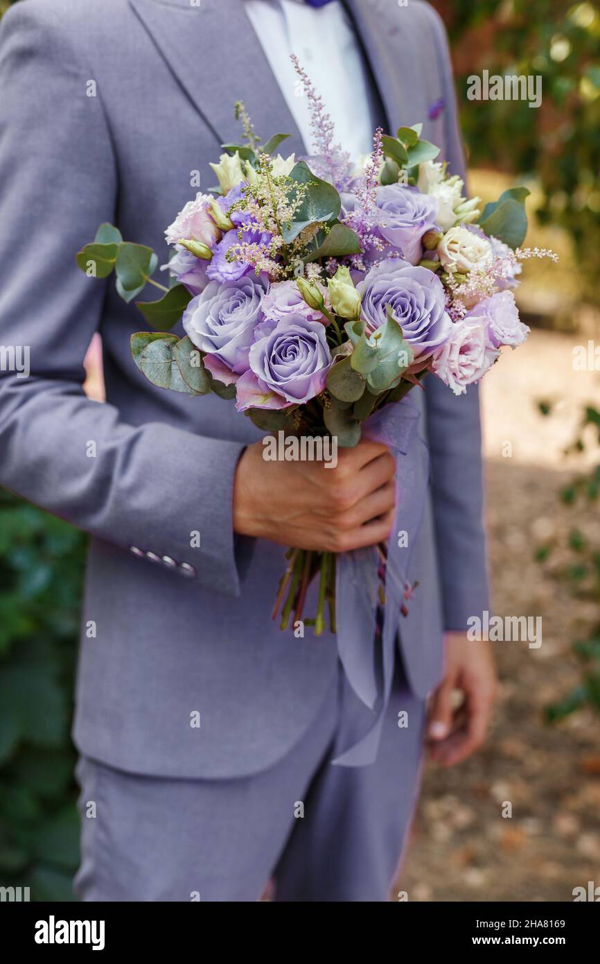 Sposi in tuta molto peri tenendo in mano bouquet di nozze, primo piano. Uomo che si prepara la mattina. Colore alla moda dell'anno 2022 in abbigliamento. Foto Stock