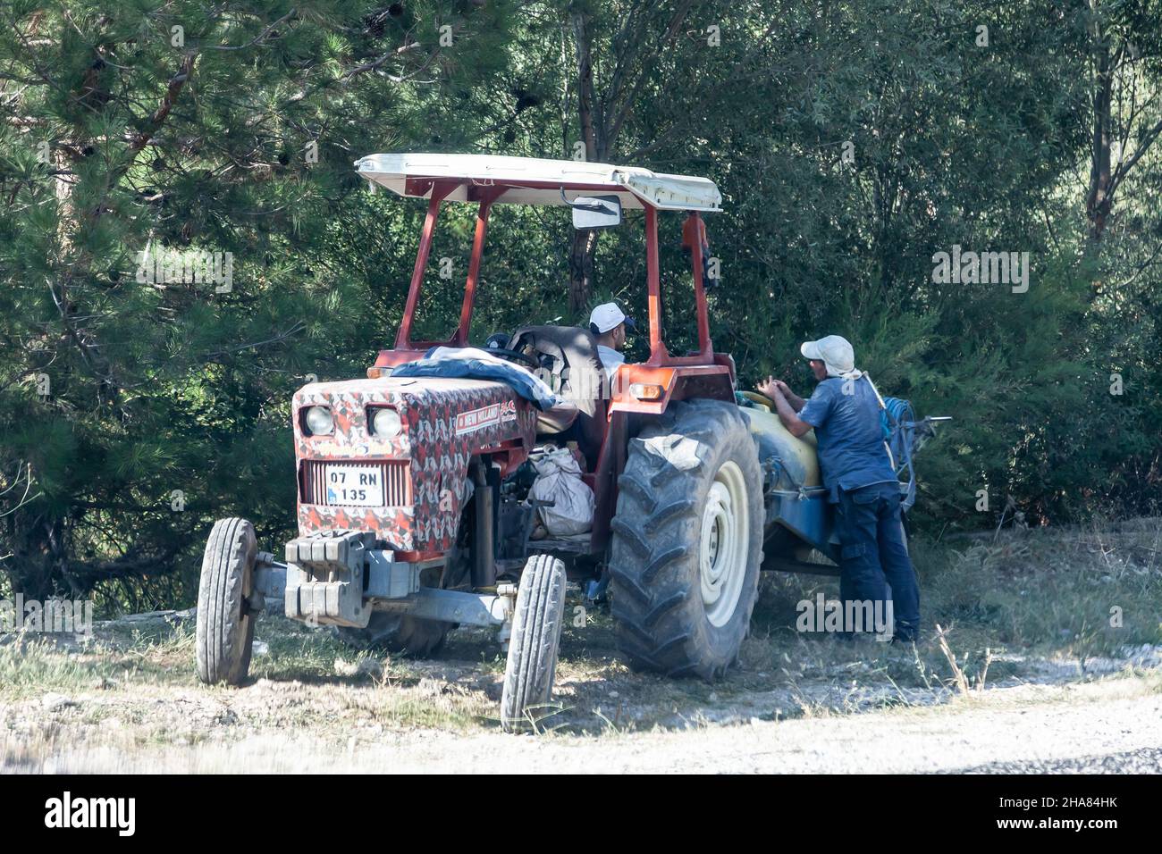 Antalya, Turchia - 08. 28. 2021: Vecchio trattore arancione di marca che guida con tre woker Foto Stock