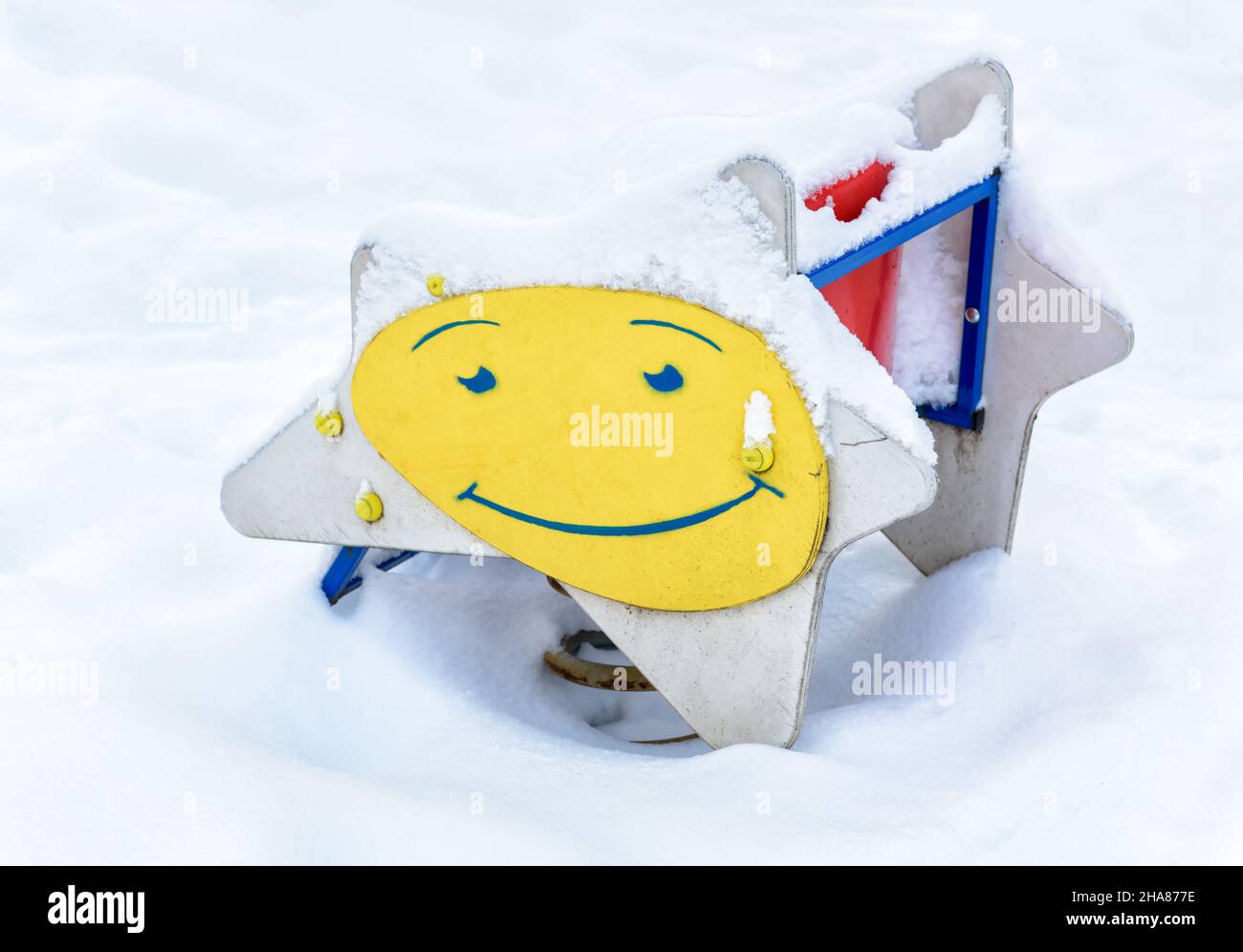 Parco giochi innevato in inverno, Mosca, Russia. Immagine del sorriso sull'altalena dei bambini, parco vuoto dopo la nevicata. Scenario di asilo sotto la neve in inverno c Foto Stock