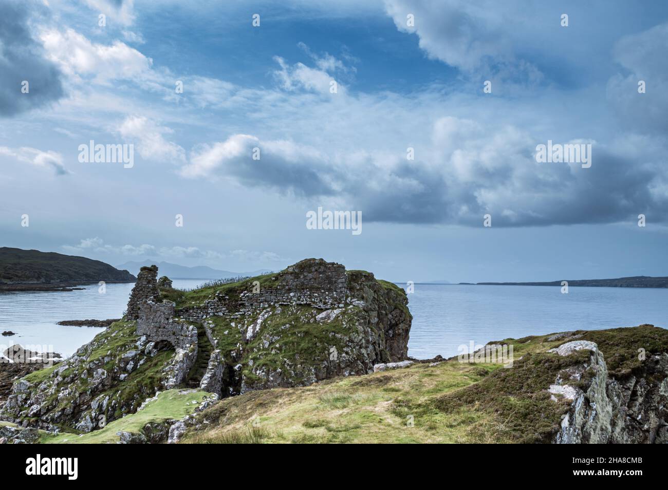Rovine del medievale castello Dunscaith contro il mare e le nuvole Foto Stock