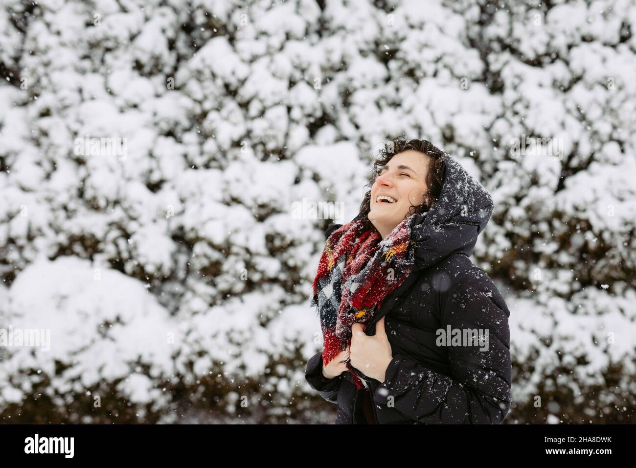 Donna in cappa e sciarpa rossa sorridendo e ridendo fuori sulla neve Foto Stock