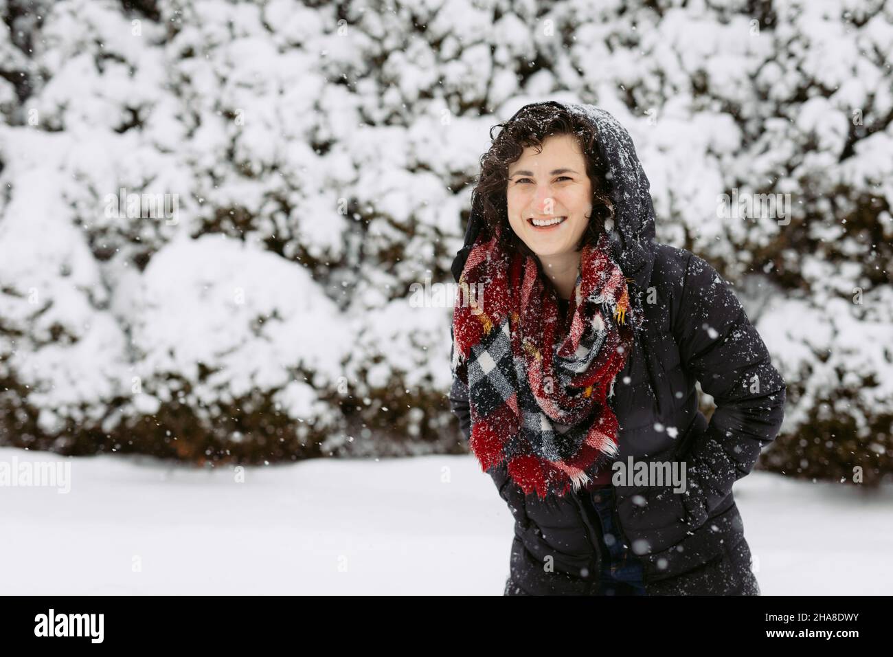 Donna in cappa e sciarpa rossa sorridendo e ridendo fuori sulla neve Foto Stock