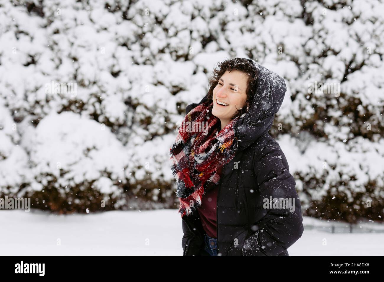 Donna in cappa e sciarpa rossa sorridendo e ridendo fuori sulla neve Foto Stock